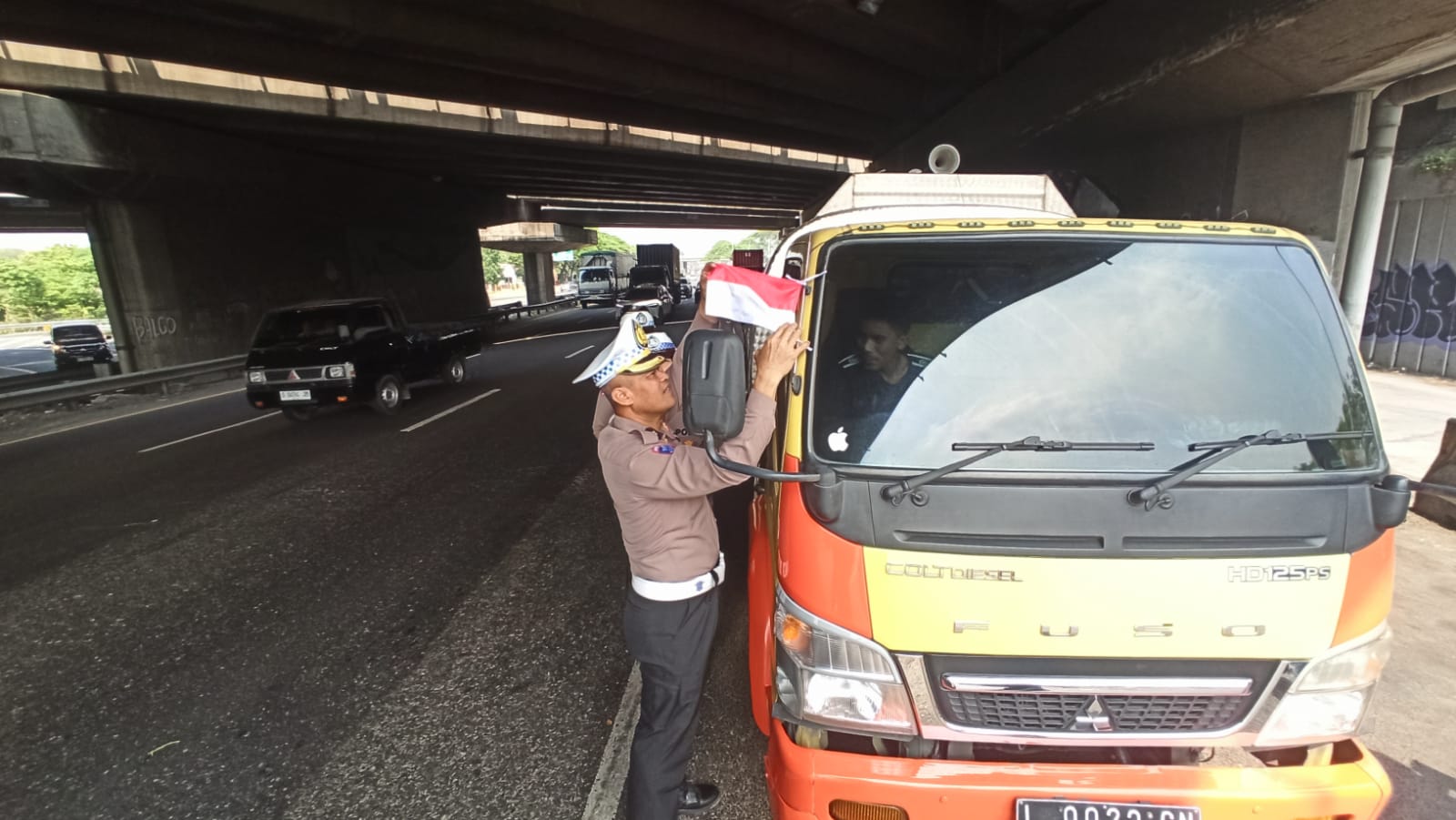 Sambut HUT RI ke-80 Ditlantas Polda Jatim Bagikan Bendera Merah Putih ke Sopir Truk